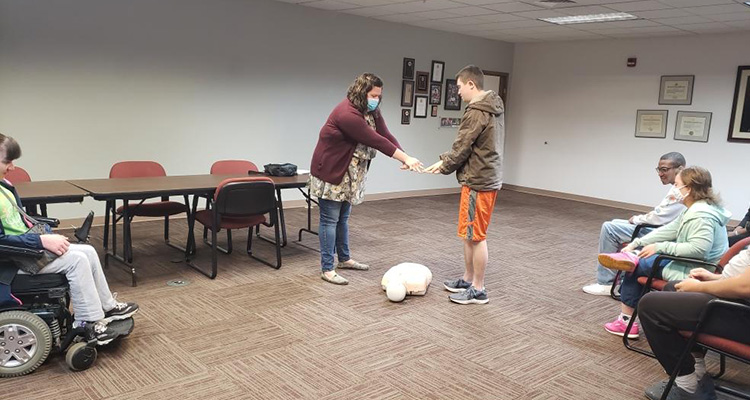 EchoingU Southwest Ohio learning CPR. Student is learning how to place his hands on the chest of the CPR test body.