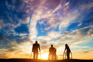 People with disabilities looking at a sunset. Beautiful blue sky with setting sun and white clouds.