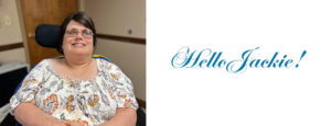 Meet Jackie. A brunette smiling in a colorful shirt that has a paisley print