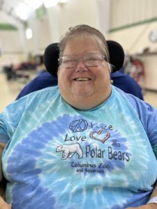 Helen smiling happily. Wearing glasses and a tie dye blue t-shirt. 