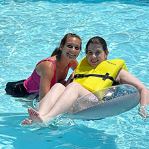 Camp Counselor and Camper having fun in the clear blue waters of the pool at Camp Echoing Hills.