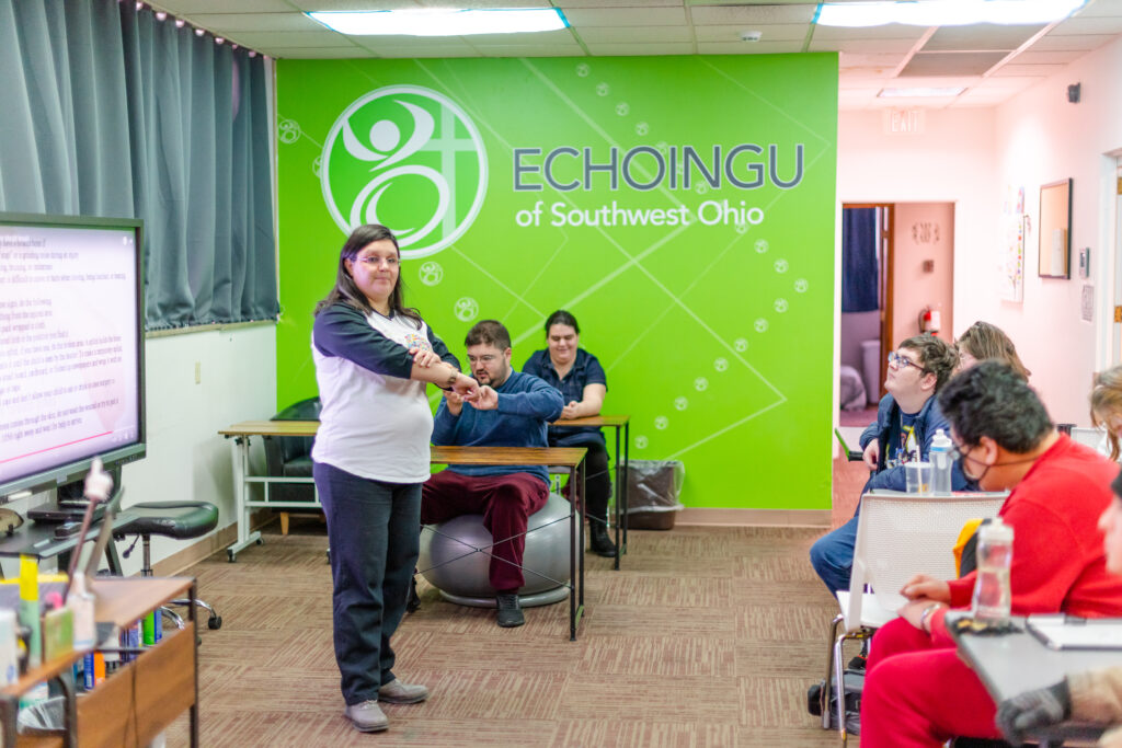 EchoingU instructor leading the class. Green banner with EchoingU logo hangs behind the students.