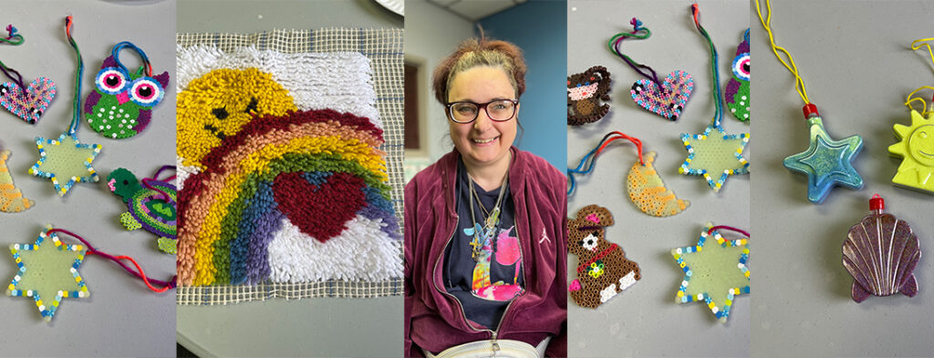 Meet Becka. Becka is pictured smiling, she wears glasses. Also in the photo is several pieces of her art. A hook rug with smiley face and rainbow among others.