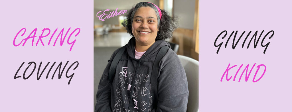 Esther smiling wearing a sweatshirt that says Angel. Smiling and happy with graying hair mixed with black. She is wearing a pretty pink headband.