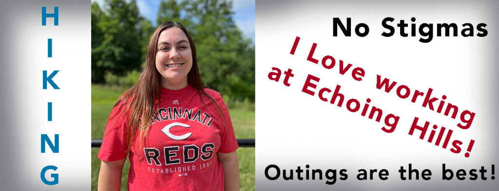 Michaela smiling wearing a red and black and gray Cincinnati Reds t-shirt. She has long brown hair.