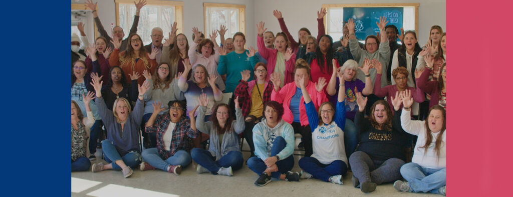 Picture of Echoing Hills team members smiling with hands in the air. They are Champions. Some are wearing logo apparel with the Echoing Hills wheelchair symbol in the logo.