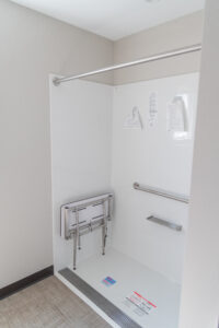 Interior shows large shower with grab bars and shower seat.