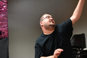 Showing his fun side in a black t-shirt, smiling face and cool dance moves with hands in the air.